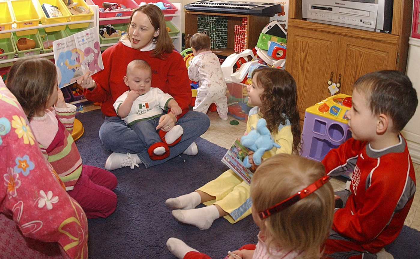 family child care provider reading to a group of young children