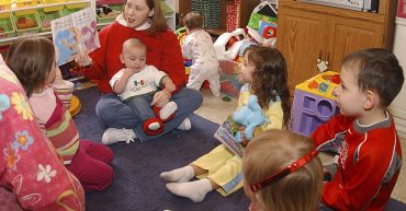 family child care provider reading to a group of young children