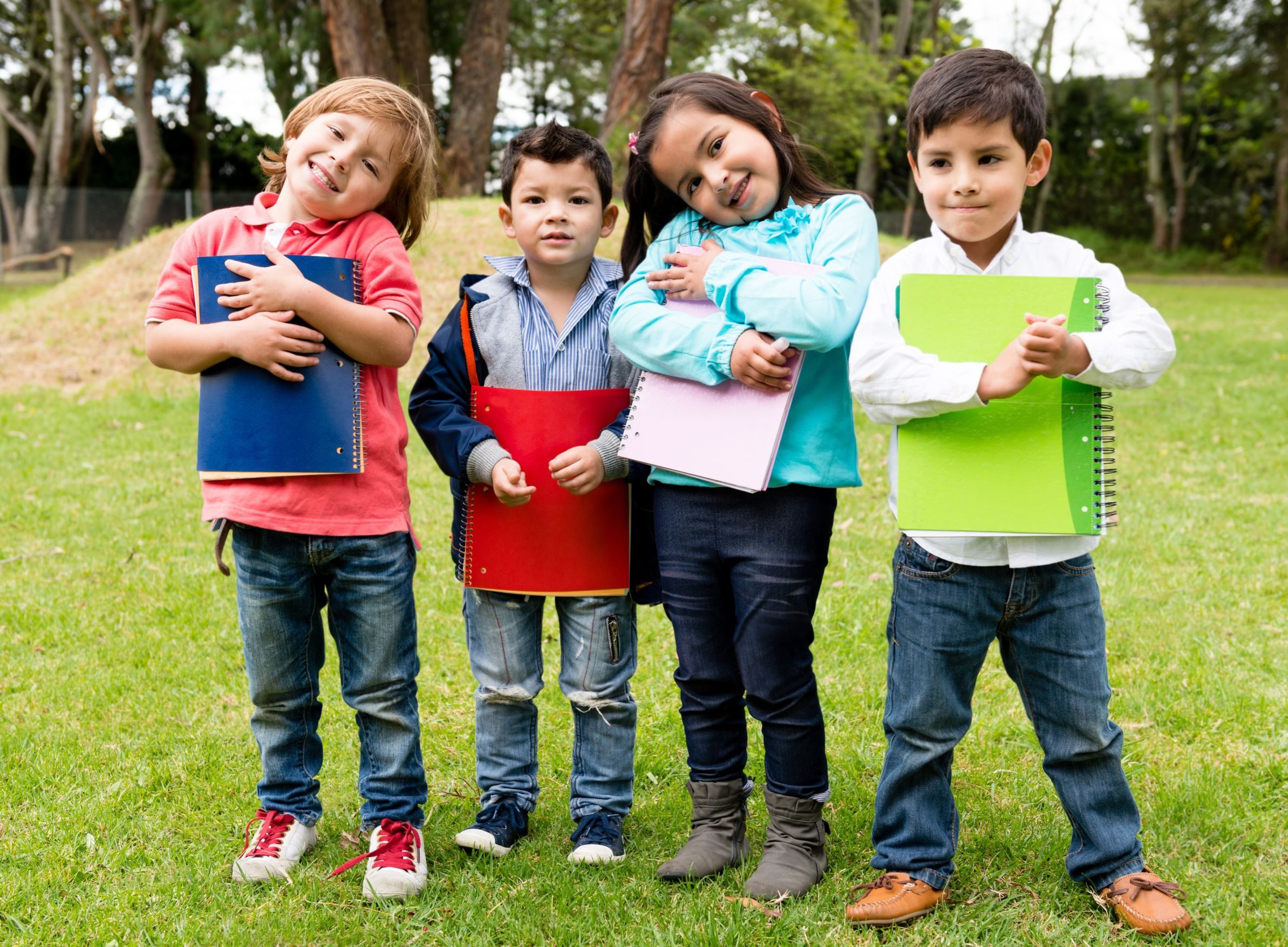 Four young children holding notebooks