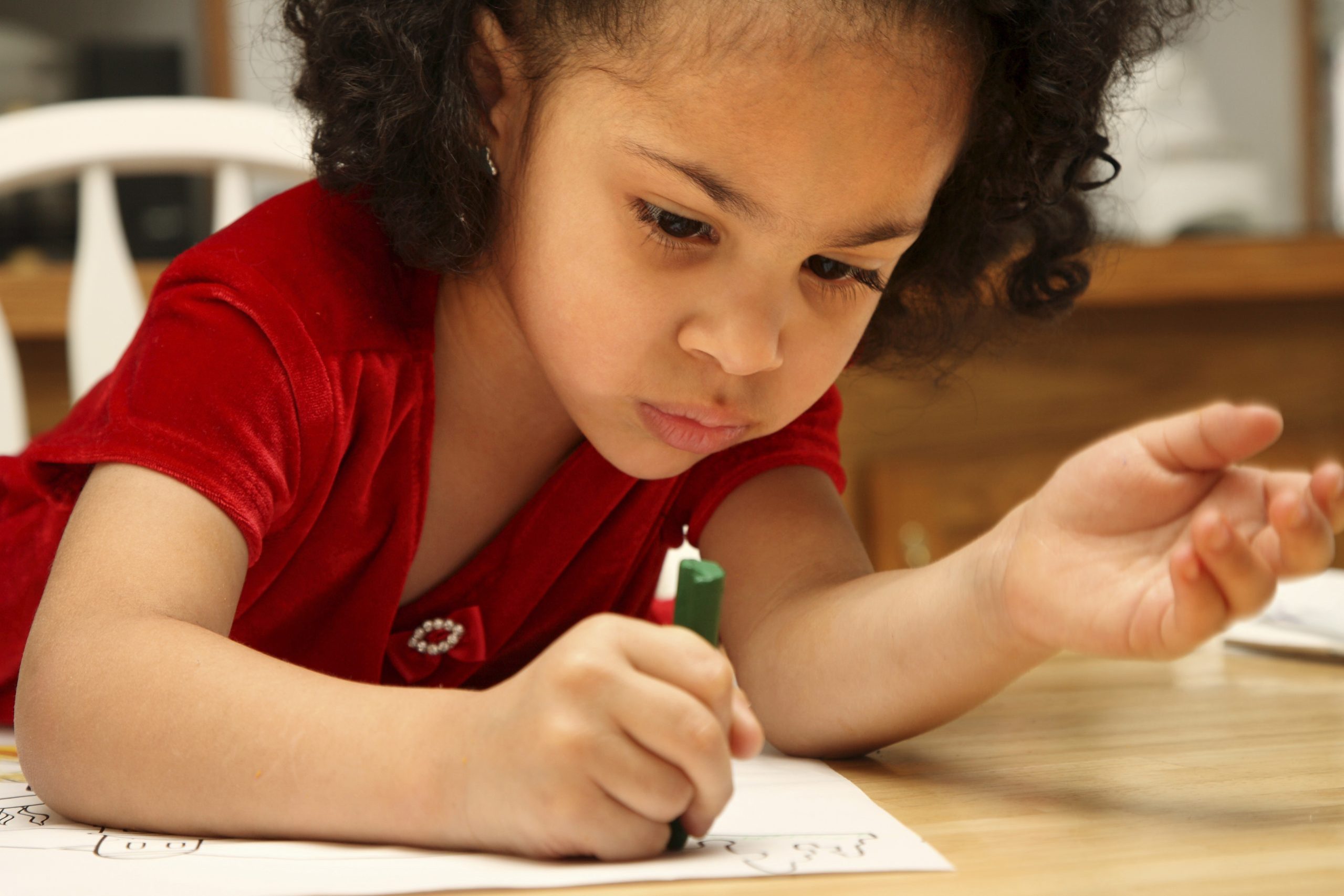 young girl writing on paper at a table
